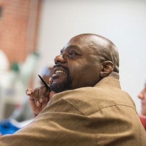 Man in brown shirt holding pen